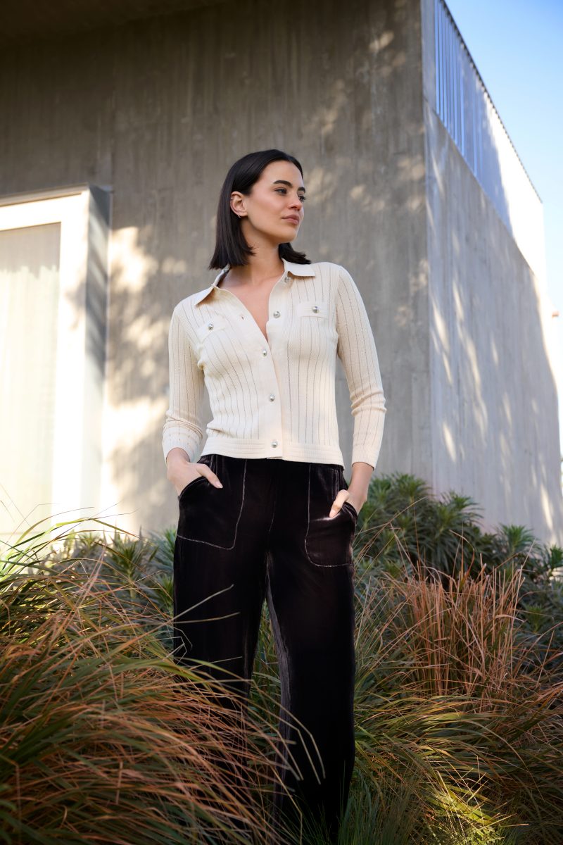Model wearing knitted top outside amongst some tall grass