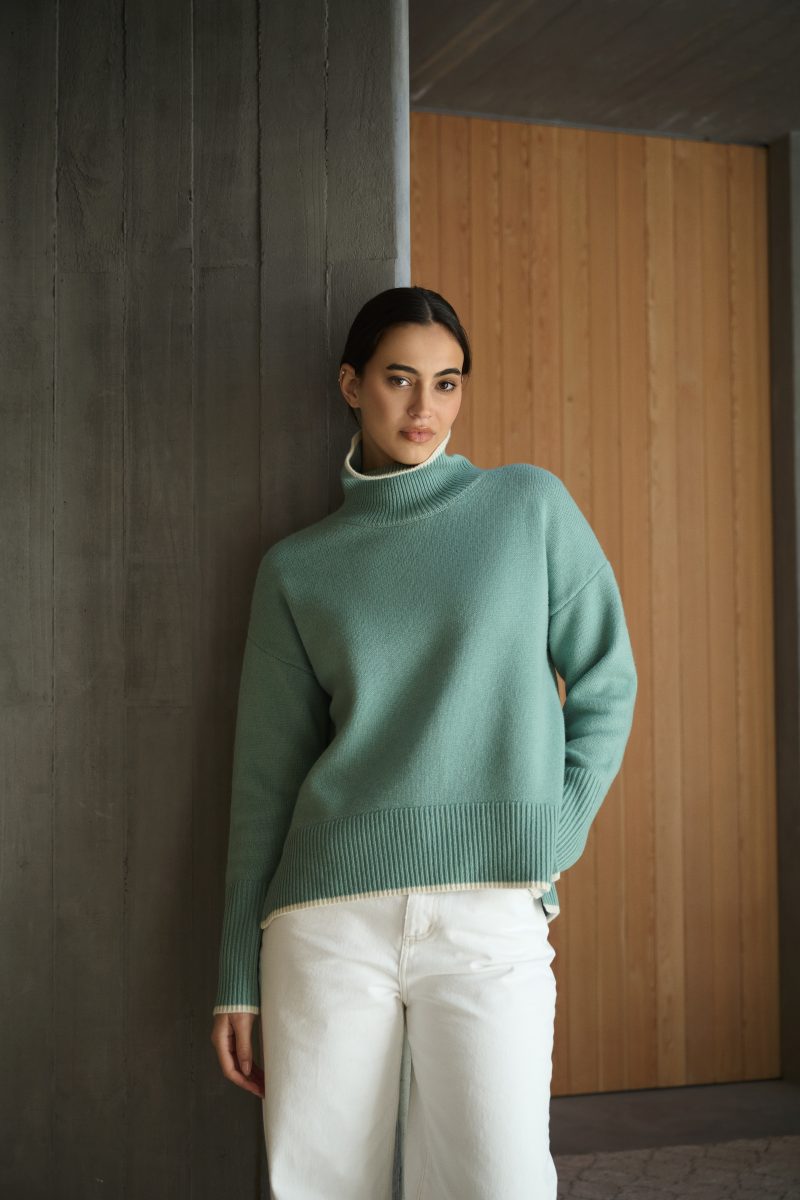 Model wearing knitted top leaning against a wall